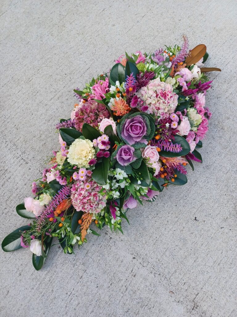 Kin Florist casket spray featuring locally grown purple, orange, and pink flowers, for a Warkworth service at Jason Morrison Funerals.