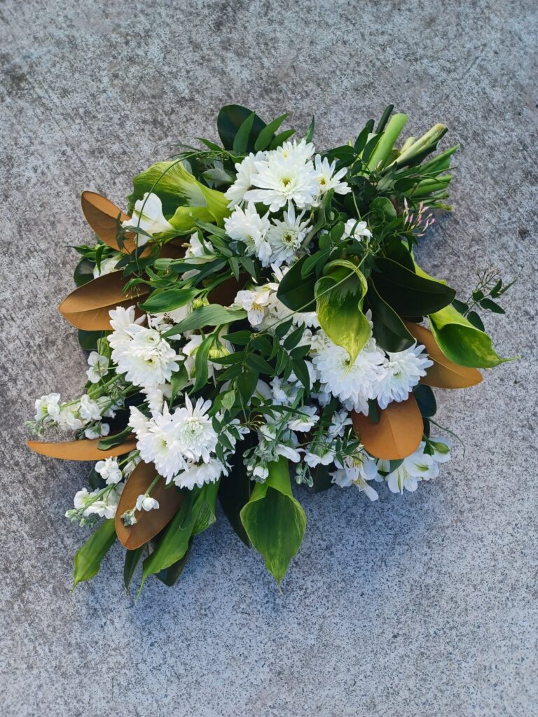 Kin Florist Matakana hand tied, foam free casket sheaf, featuring green and white flowers and foliage, for a Warkworth funeral service.