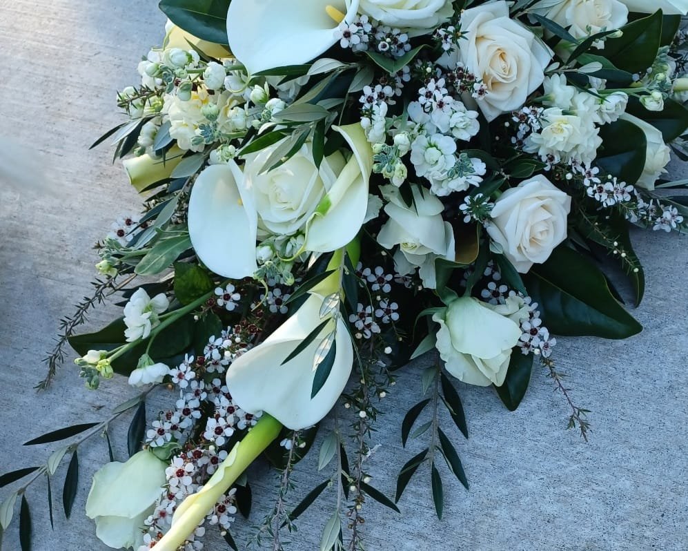 Kin Florist casket spray with white roses, white lillies, and white flowers, for a funeral service at a Warkworth church.