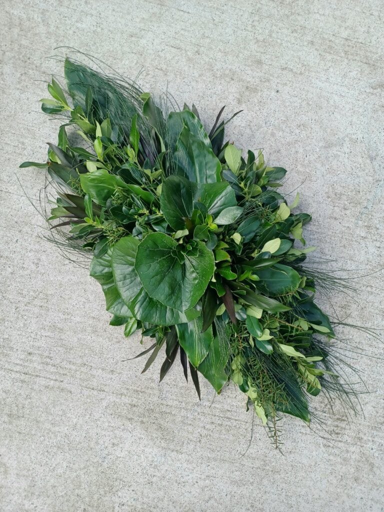 Masculine, natural foliage casket spray by Kin Florist for a Warkworth funeral. The casket features a selection of rich, lush greenery including native totara and coprosma. An affordable option for a man.
