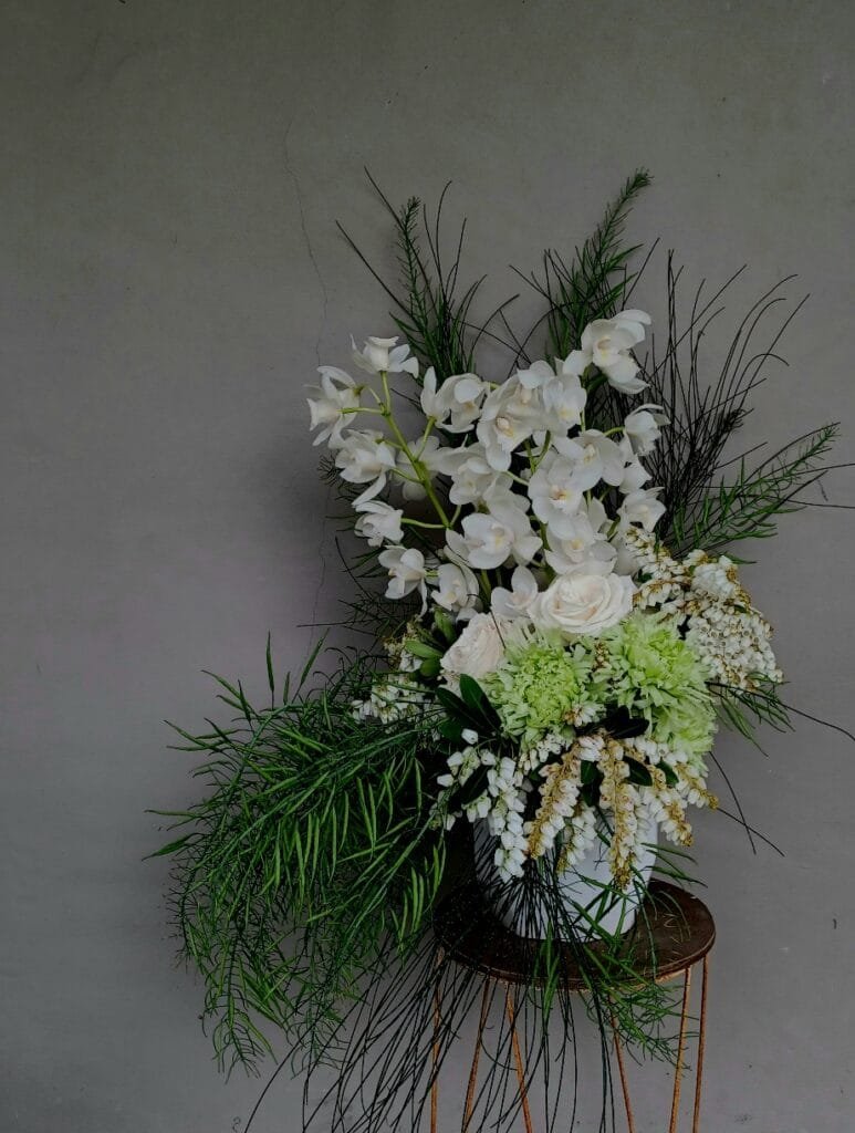 Kin Florist Matakana wedding arrangement with white orchids, white roses, and cascading seed pods, suitable for a wedding bar or accent piece.
